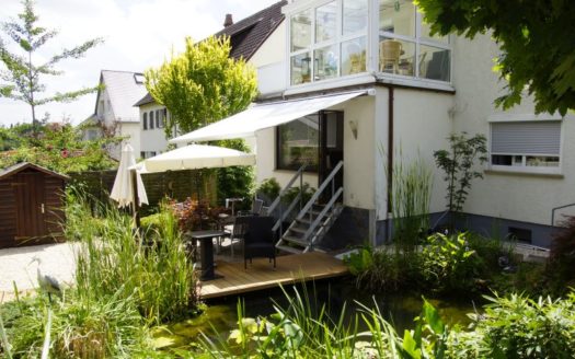 Aussenbereich eines Hauses mit Wintergarten Terrasse und Teich