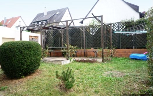 Gartenwiese mit Holzzaunbegrenzung und Häusern im Hintergrund
