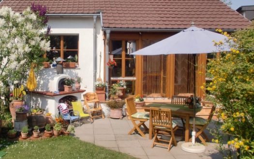 Gepflasterte Terrasse mit Ampelschirm, Steinofen und Teakholzmöbeln