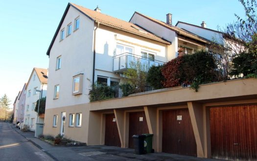 Reihenhaus mit kleinen Fenstern, Balkon und vier Garagen