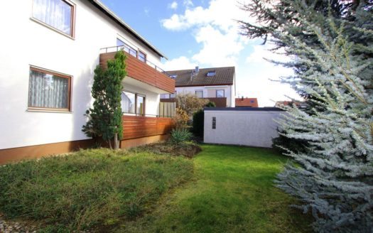 Seitenansicht Mehrfamilienhaus mit Garten und Blautanne im Vordergrund