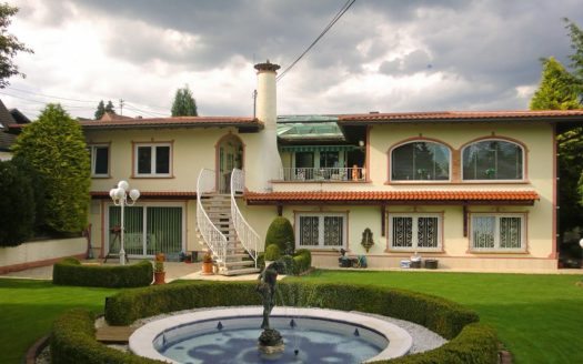 Steinerner Wasserspeier vor toskanischer zweistöckiger Villa