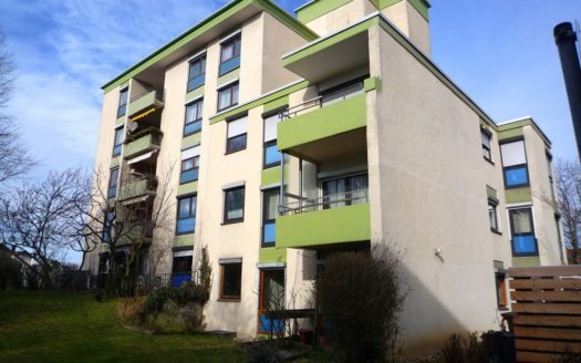 Wohnhaus mit grün gestrichenen Balkonen und Vorgarten