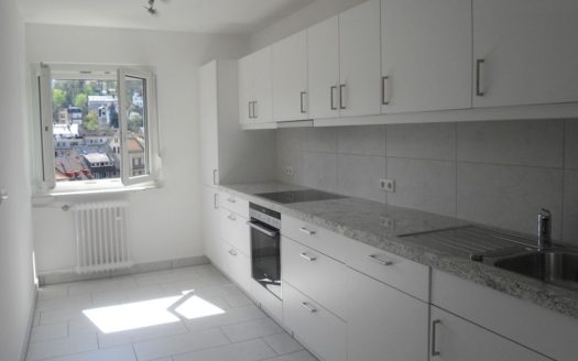 Weiße Einbauküche mit hellem Fliesenboden und mittelgroßem Fenster