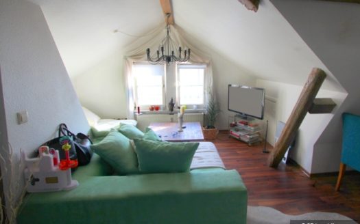 Dachzimmer mit mintfarbenem Sofa und Metallkronleuchter