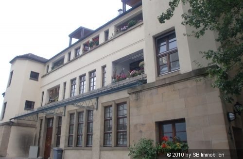 Blick auf älteres Haus mit hohen Gitterfenstern und weißem Turm