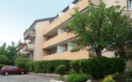 Kfz-Stellplätze vor Wohnhaus mit hellen Balkonen