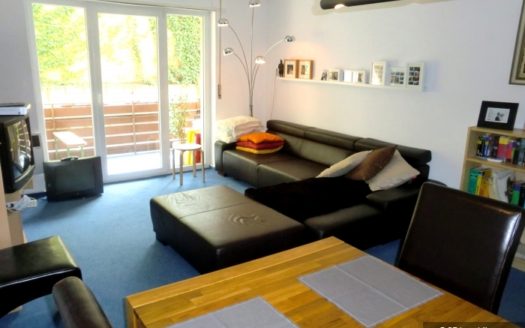 Kombinierter Wohnraum mit schwarzem Ledersofa und Holzesstisch